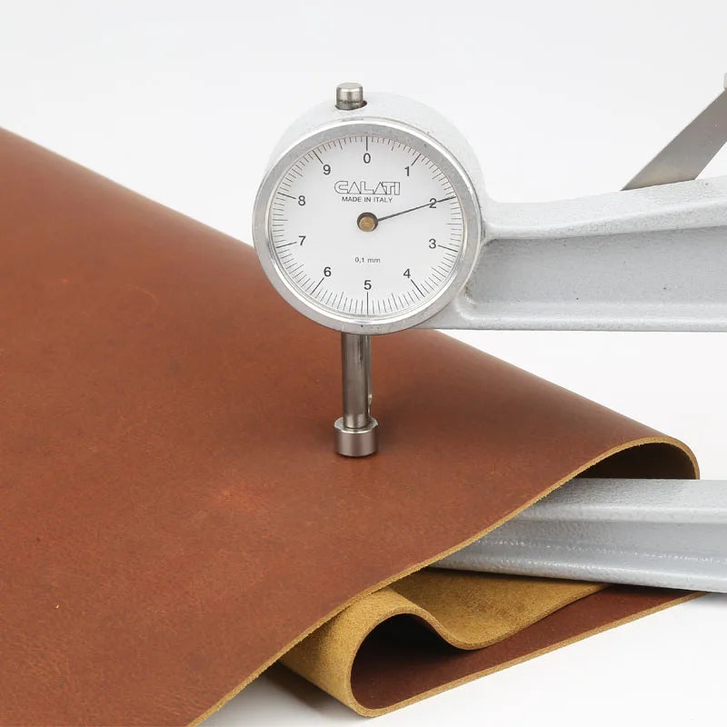 A brass caliper measuring 1.8mm leather hide in rust red color against a white background.