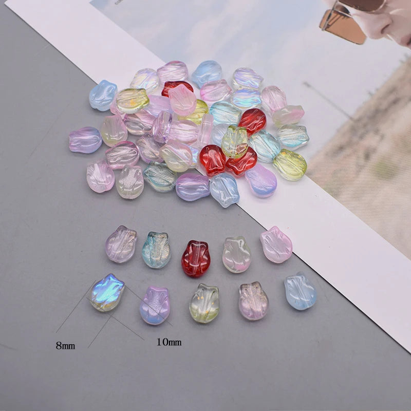 A collection of iridescent glass beads in various shades of pink, purple, and blue scattered on a white surface.