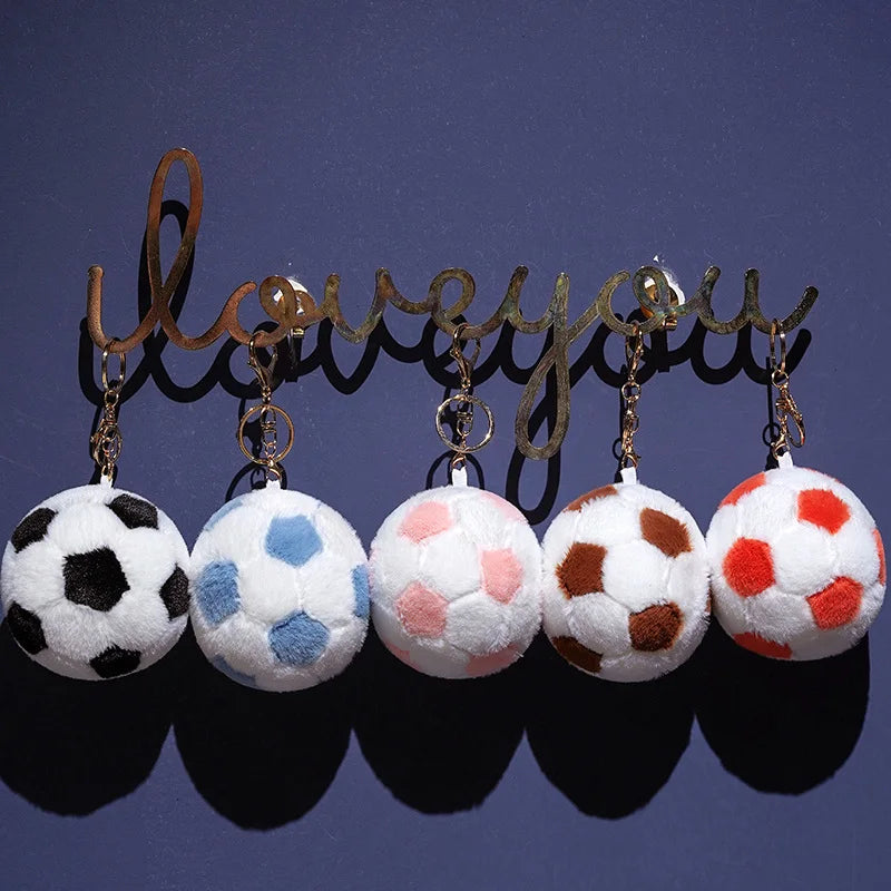 A row of realistic football plush pillows in various colors and patterns, suspended by gold-toned chains.