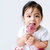 A baby is holding a pink sensory teething rattle designed for babies.