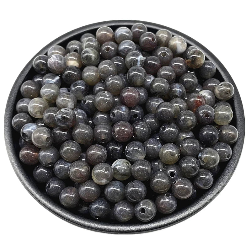 A pile of dark gray and brown acrylic round beads for jewelry making.