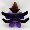 A plush toy featuring a brown witch hat and black, curved ears on a purple body.