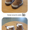 A pair of brown suede winter boots with fluffy cream lining and yellow accents resting on a wooden table.