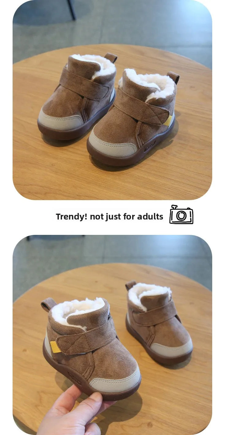 A pair of brown suede winter boots with fluffy cream lining and yellow accents resting on a wooden table.