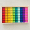 A wooden tray filled with colorful rainbow acrylic building blocks arranged in a grid.