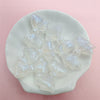 Clear iridescent mermaid bowknot beads arranged on a white dish for jewelry making