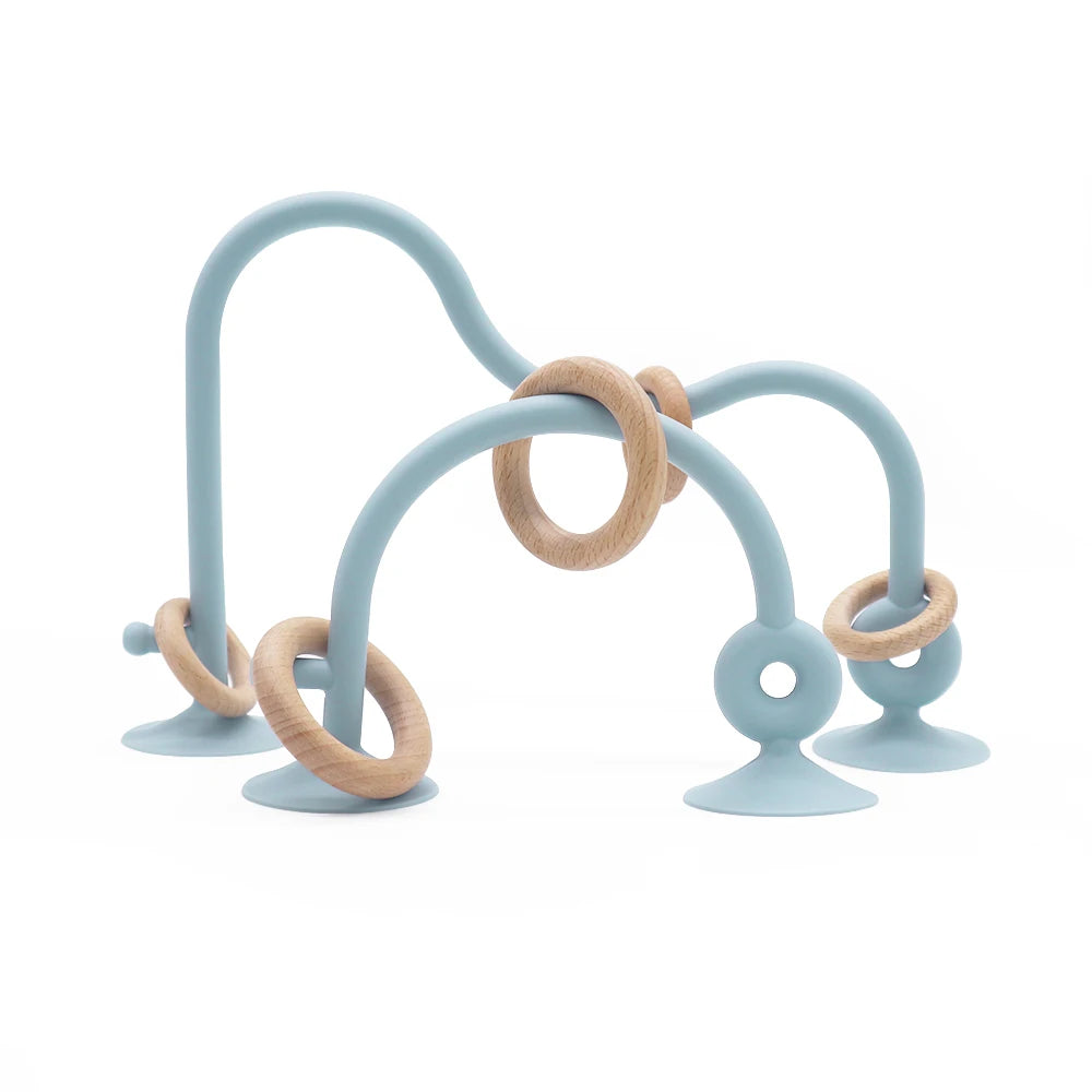 A set of soft silicone teether rings in light blue and natural wood tones.
