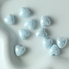 A collection of light blue heart-shaped ceramic beads scattered on a white surface.