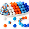 A collection of soft food-grade silicone beads in various colors including white, orange, and blue arranged in a line.