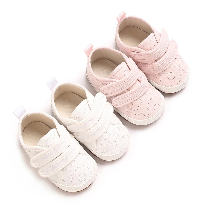 Pair of pink soft-sole baby first walkers with adjustable straps shown from the top view.