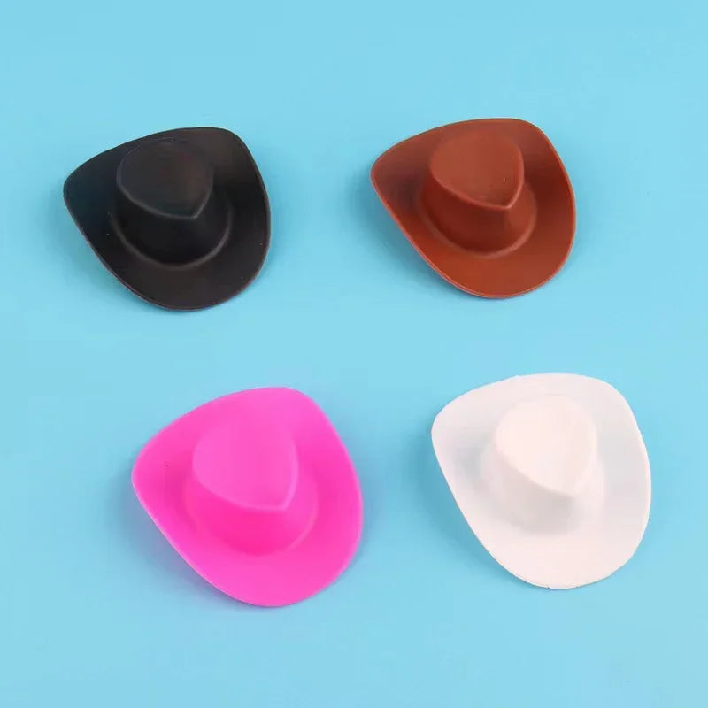 A set of three mini rubber duck accessories including a black hat, a brown hat, and a pink and white hat.