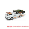A 1:64 scale diecast truck with a trailer, featuring a black and orange custom vehicle.