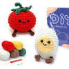A beginner crochet kit for amigurumi animals showing a red strawberry, a white animal, and yarn with a needle.