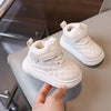 A pair of white quilted toddler winter snow boots with soft lining and velcro closure resting on a light surface.