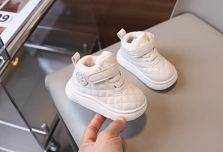 A pair of white quilted toddler winter snow boots with soft lining and velcro closure resting on a light surface.