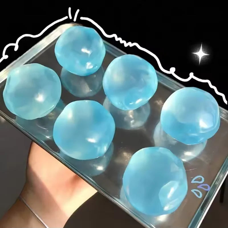 A hand holds a clear container filled with light blue squeezable soft fidget balls for stress relief.