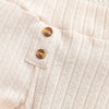 Close-up of a light pink knitted baby romper and pants set with wooden buttons.