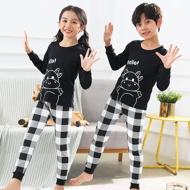 Two children wearing black long-sleeved tops and checkered pants with an astronaut print
