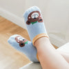 A pair of light blue cotton cartoon animal socks with brown bear designs and orange grips worn on a person's foot.