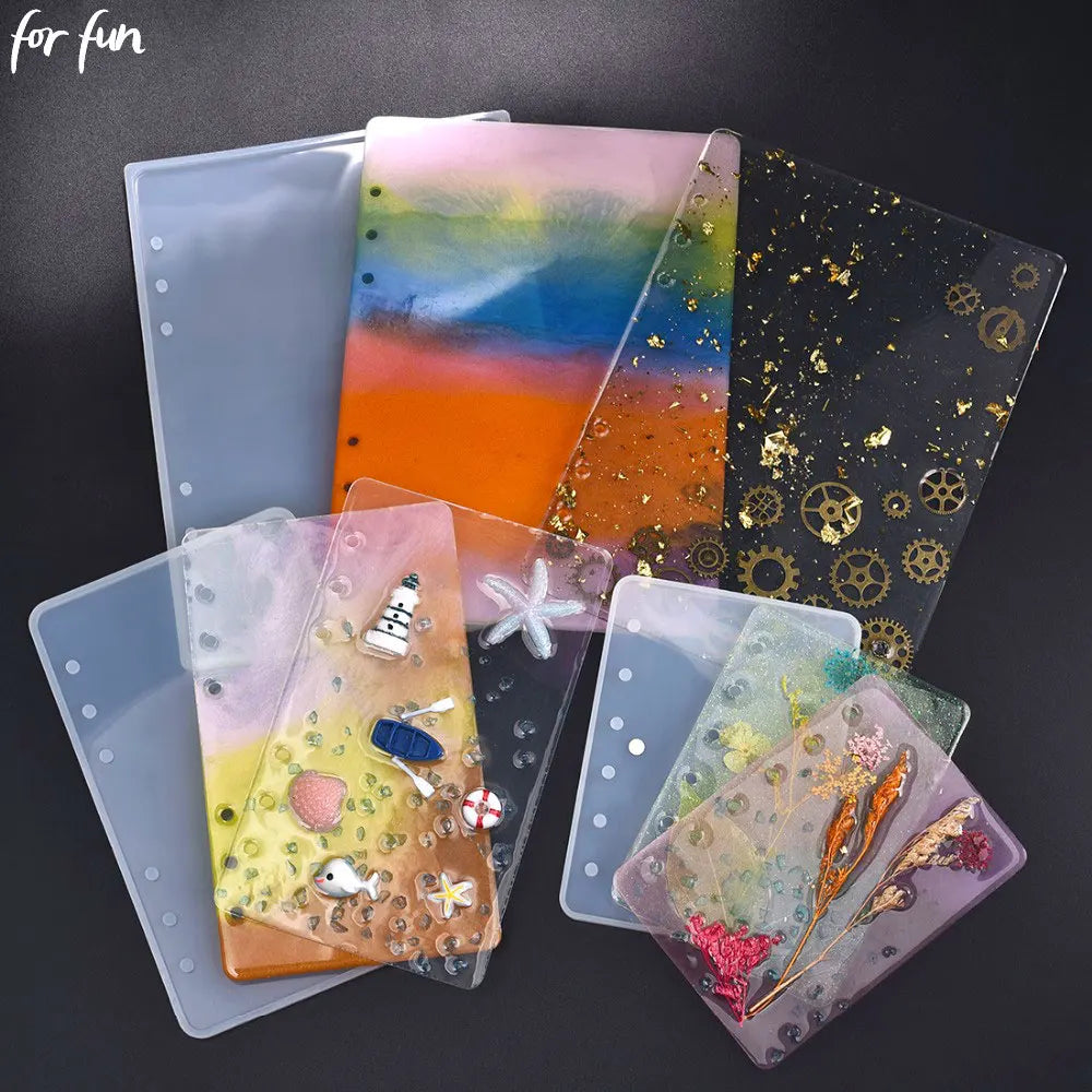 A collection of colorful epoxy resin notebook covers in various shades and patterns displayed on a dark background.