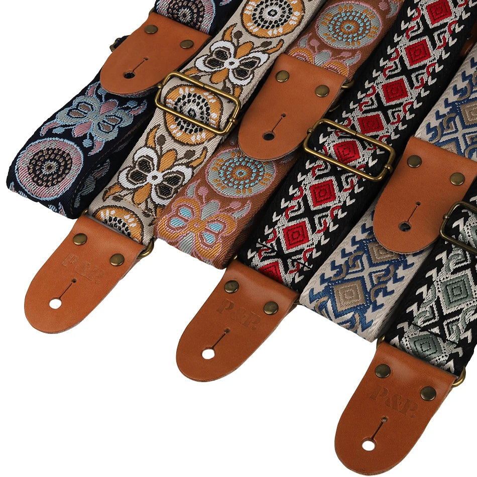 Embroidered guitar strap featuring various patterns on fabric with leather ends.