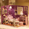 A detailed wooden miniature dollhouse kit featuring pink and white furniture, including a bed, cabinet, and window.