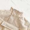 A beige fleece-lined winter coat with a half-zip collar and ribbed texture is shown on a white background.