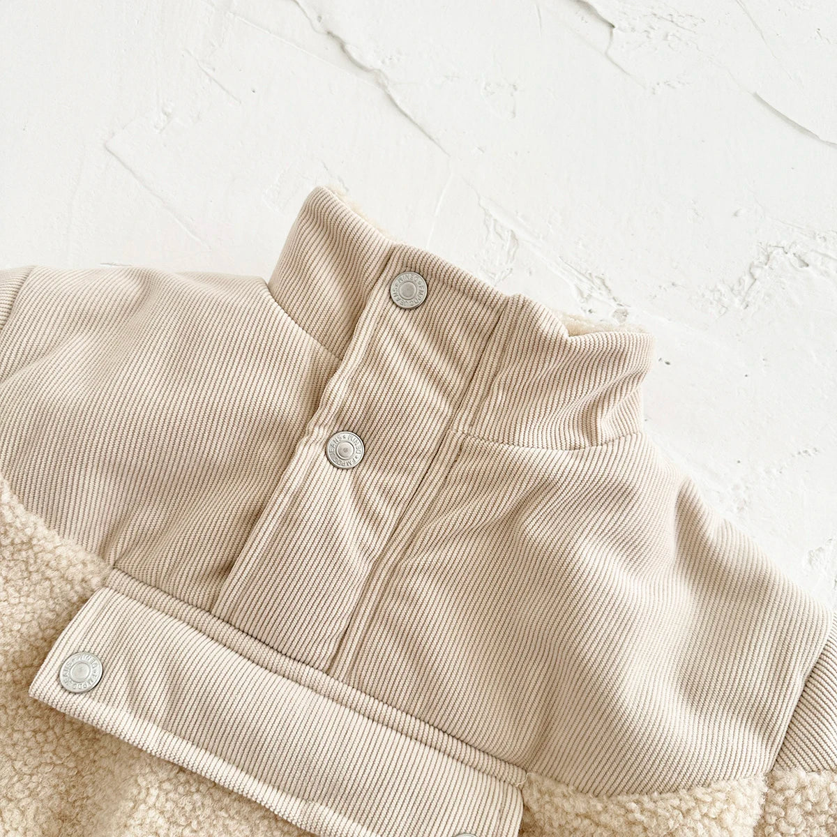 A beige fleece-lined winter coat with a half-zip collar and ribbed texture is shown on a white background.