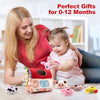 A baby is playing with a pink plush farm animal toy in front of a wooden box and other soft toys.