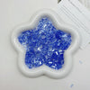 A white, flower-shaped mold filled with blue iridescent acrylic ice strips for nail art and crafts.