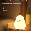 A glowing pear-shaped night light rests on a wooden surface next to a potted plant.