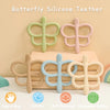 A set of soft silicone butterfly teethers in various pastel colors resting on a wooden surface.