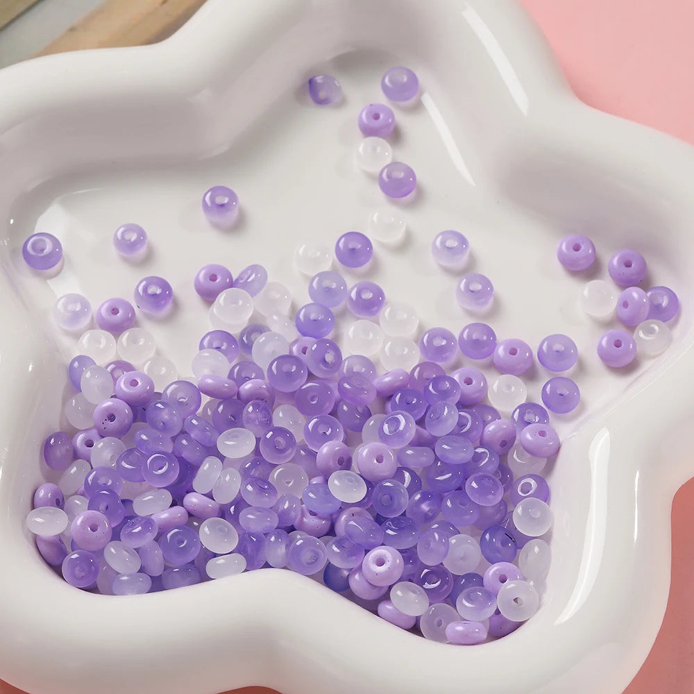 A white dish filled with purple and clear glass spacer beads.