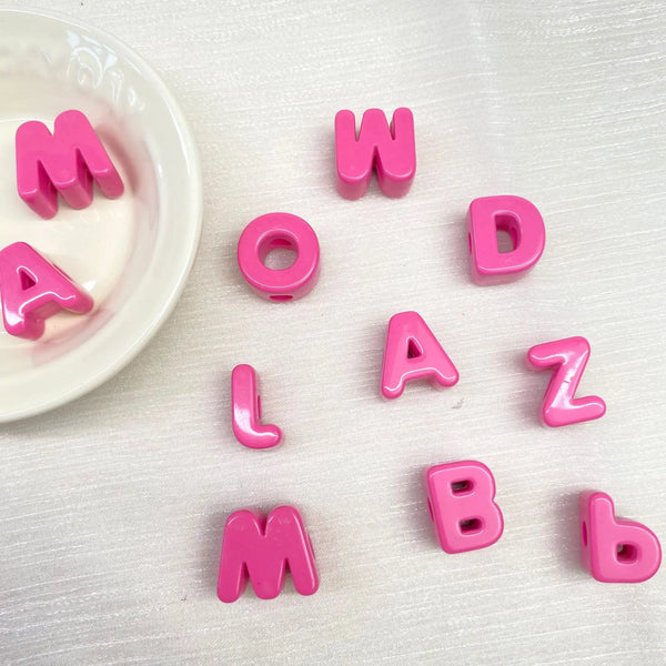 Pink acrylic letter beads spelling out the word MOWLAZ and individual letters like L, A, Z, B.