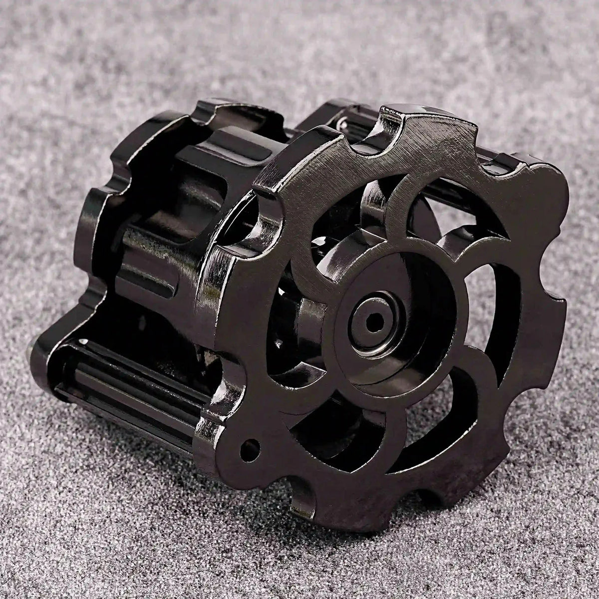 A black revolver-shaped metal dice set for RPG games resting on a gray surface.