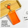 An orange retractable ID badge holder with a keychain and clip is shown resting on a wooden tray.