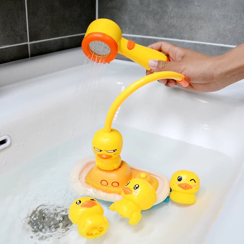 A hand is using a yellow and orange water squirter toy with duck tracks to spray water into a white bathtub.
