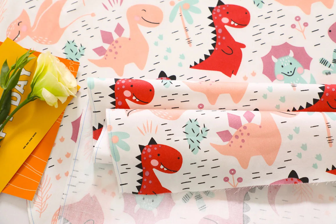 Fabric print featuring pink and red dinosaurs on a white background for sewing and DIY crafts