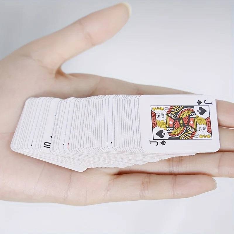 A hand holds a stack of white portable mini playing cards featuring decorative designs and card symbols.