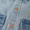 A close-up of a blue and white striped denim jacket with button details.