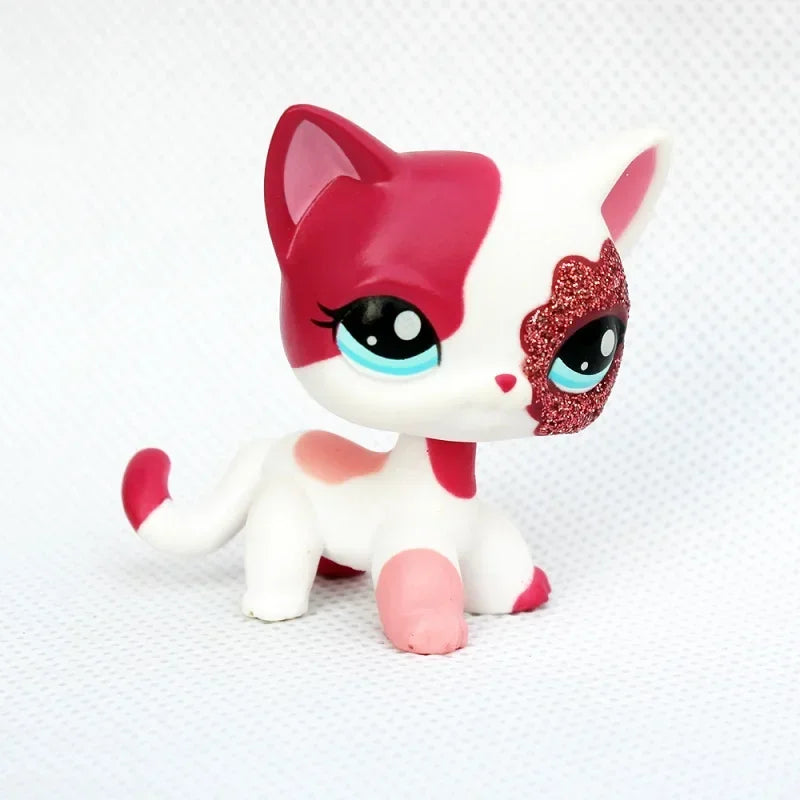 A small figurine of a kitten with white and pink fur and sparkly red eyes.