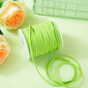 A roll of bright lime green braided ribbon for crafting and gift wrapping next to a pale orange rose.