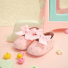 Pinke Unisex-Sandale für Säuglinge und Kleinkinder mit rosa Schleifen, auf rosa Unterlage.