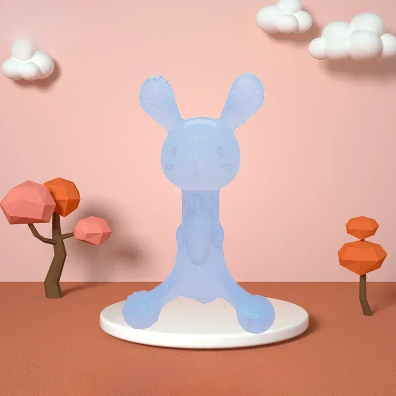 A light blue silicone teether toy shaped like a bunny stands on a white base against a pink wall.
