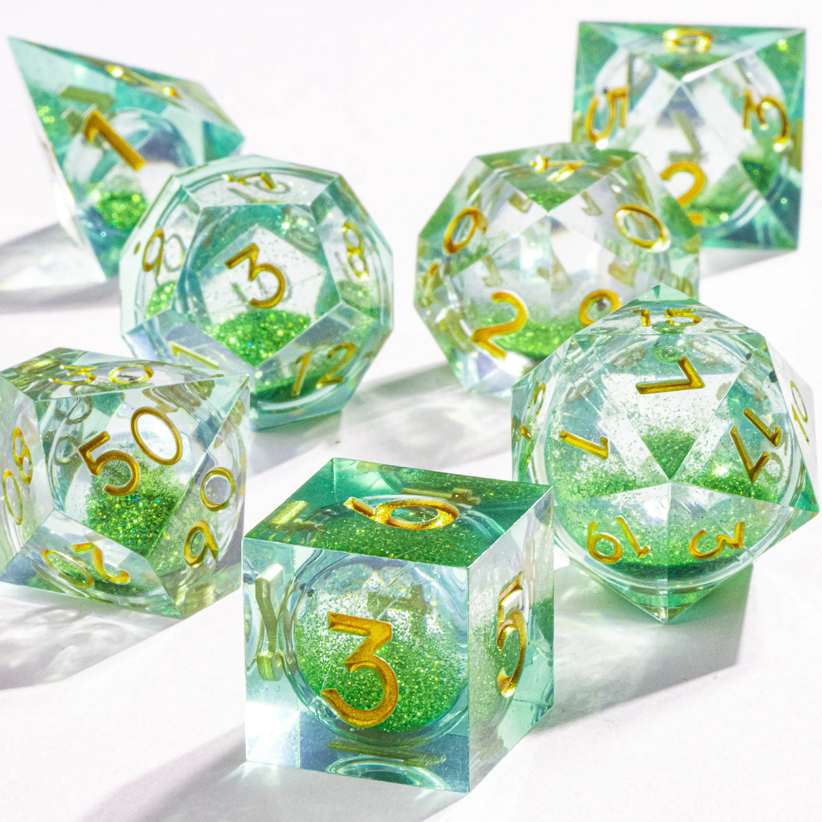 A collection of handmade liquid core polyhedral dice in various shades of green and clear glass.