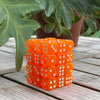 A stack of 36 transparent colorful dice set on a wooden surface next to green leaves.