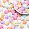 A pile of colorful, iridescent heart-shaped acrylic beads in pink, yellow, and blue shades.