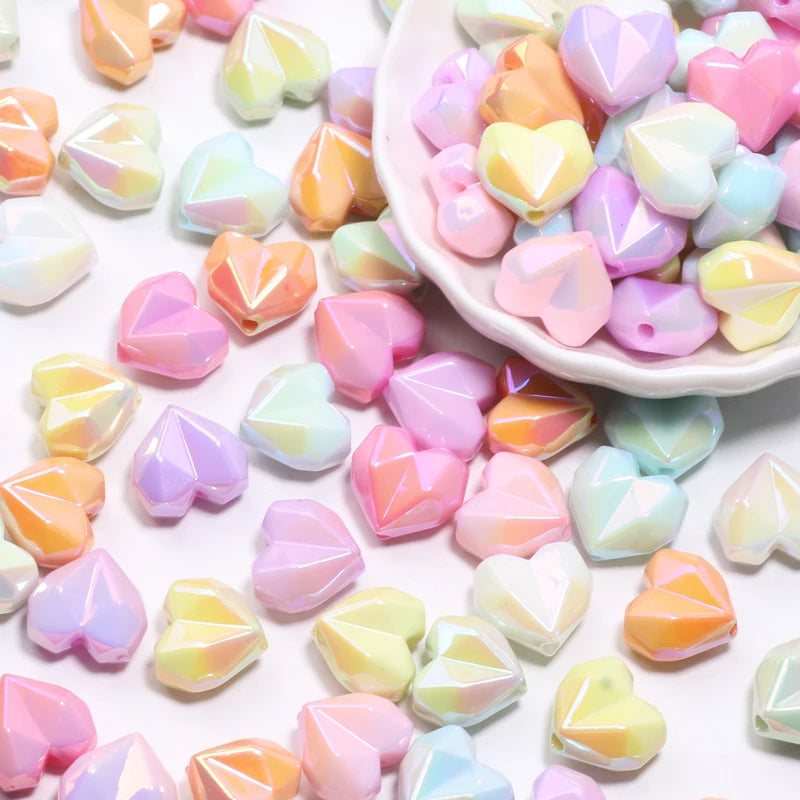 A pile of colorful, iridescent heart-shaped acrylic beads in pink, yellow, and blue shades.