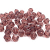 A pile of faceted bicone crystal glass beads in a rosy pink color for jewelry making