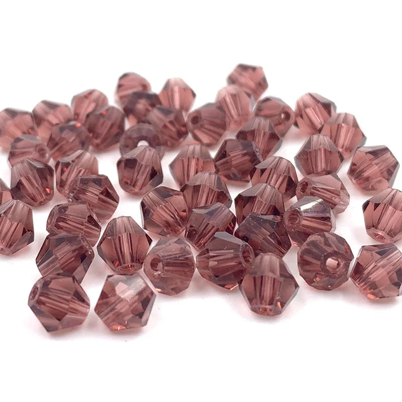 A pile of faceted bicone crystal glass beads in a rosy pink color for jewelry making